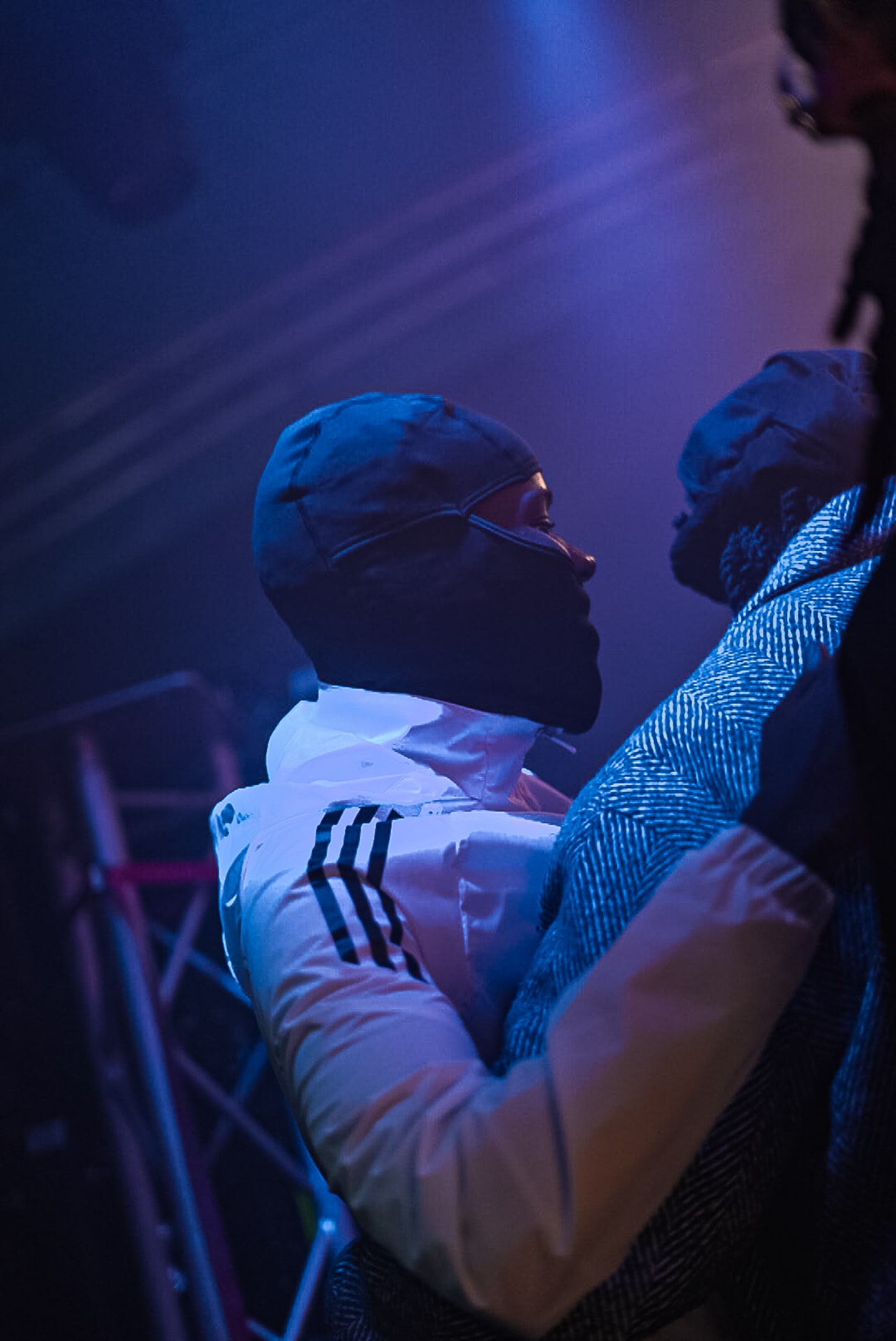 Rappeur au micro sous les projecteurs violets, veste blanche