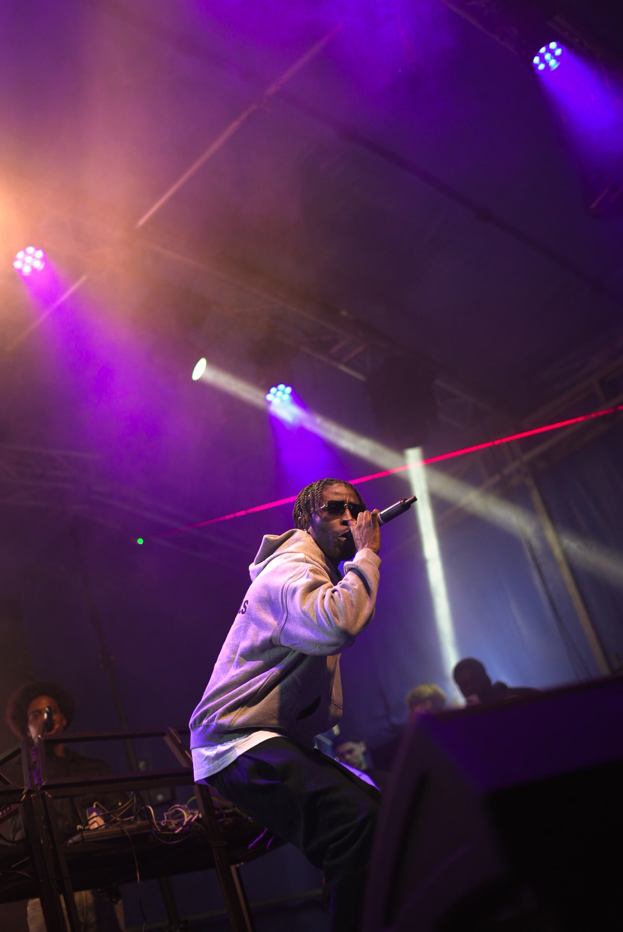 Rappeur en contre-plongée, laser rouge et DJ en fond