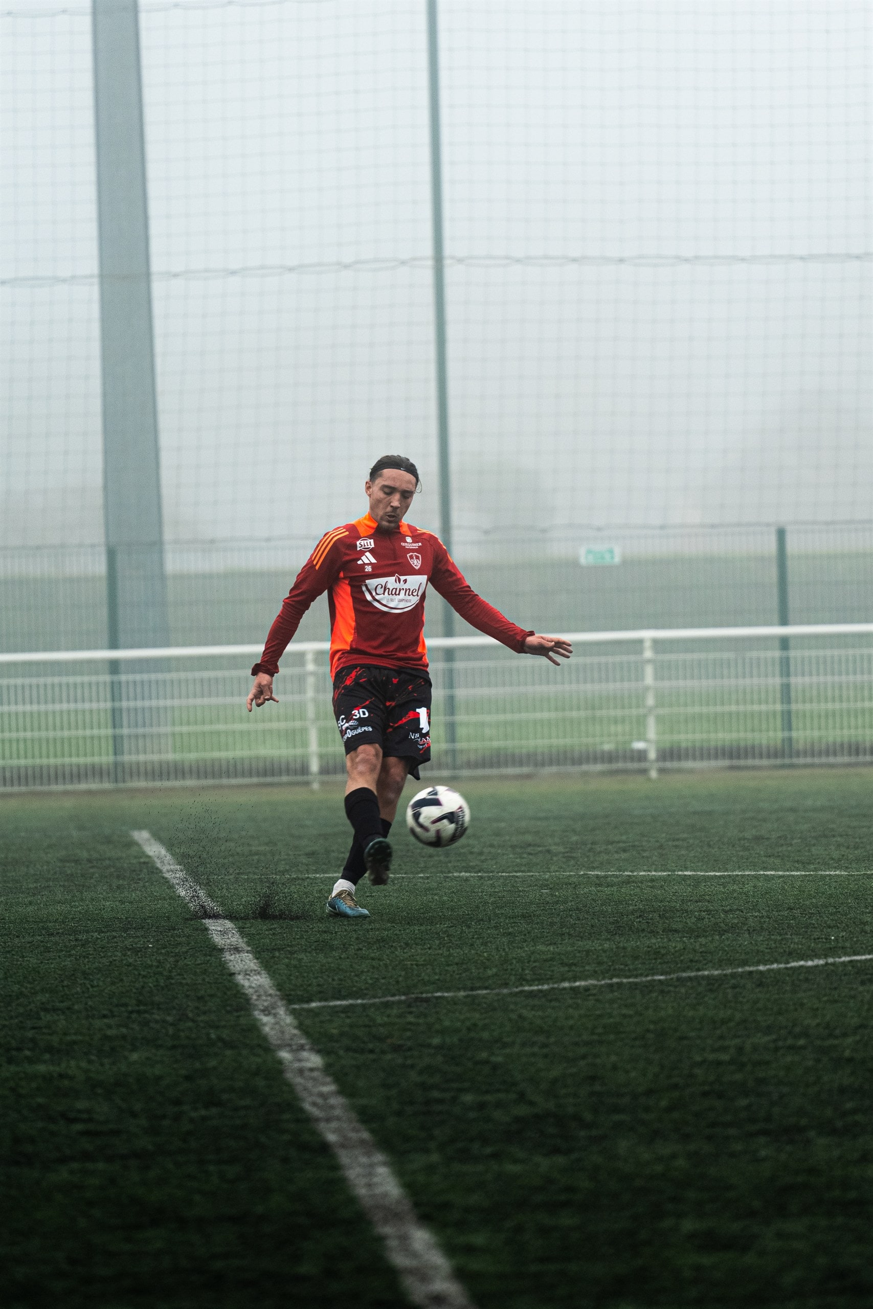 Match de football sur pelouse embrumée, action isolée
